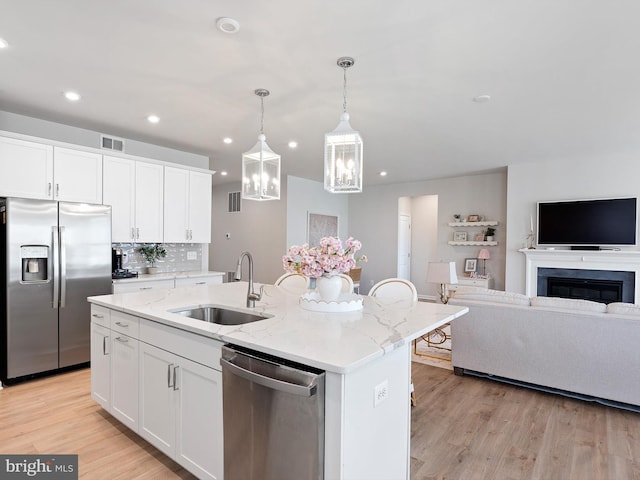 kitchen with appliances with stainless steel finishes, light wood-type flooring, a sink, visible vents, and open floor plan