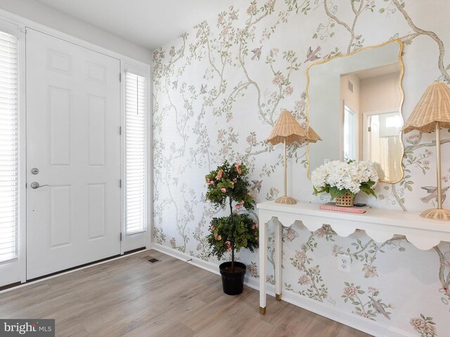 entrance foyer featuring a wealth of natural light, wood finished floors, wallpapered walls, and baseboards