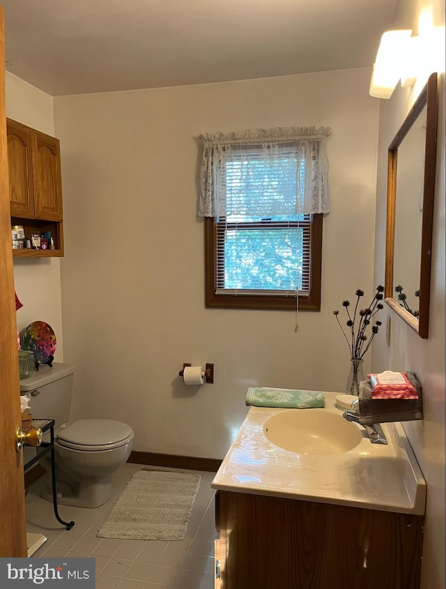 half bath with toilet, tile patterned floors, and vanity