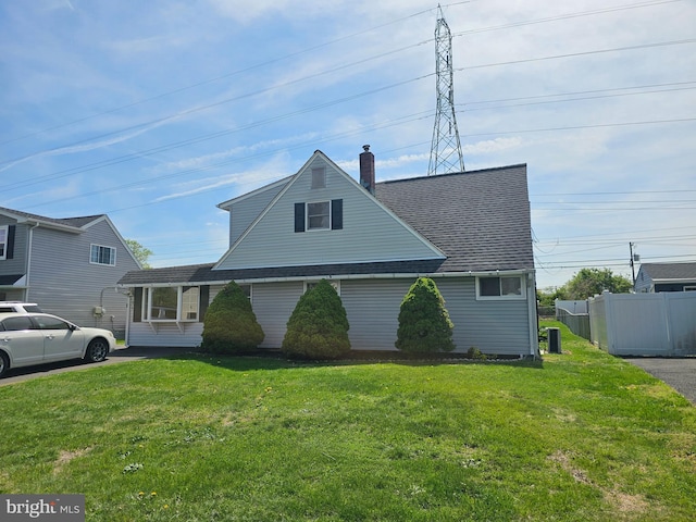 56 Coral Ln, Levittown, PA 19055 - traditional-style house featuring a chimney, fence, a shingled roof, and a front lawn