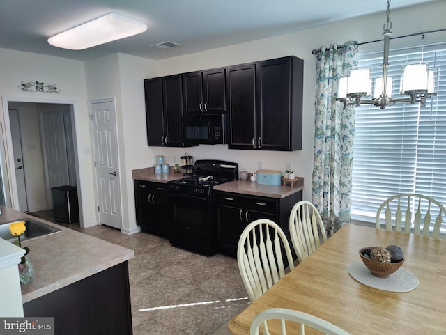 117 E Clarendon Dr, Smyrna, DE 19977 - kitchen with decorative light fixtures, light countertops, black appliances, dark cabinetry, and visible vents