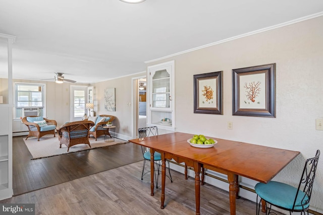 dining room featuring ceiling fan, crown molding, wood finished floors, baseboards, and cooling unit