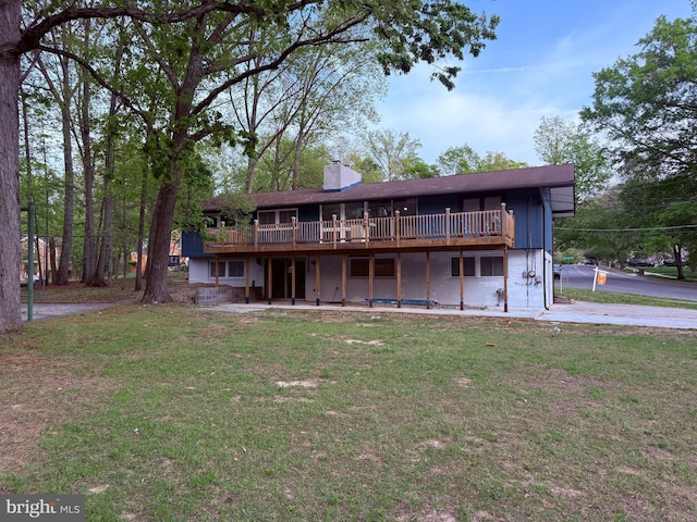 rear view of house featuring a lawn, a chimney, and a deck