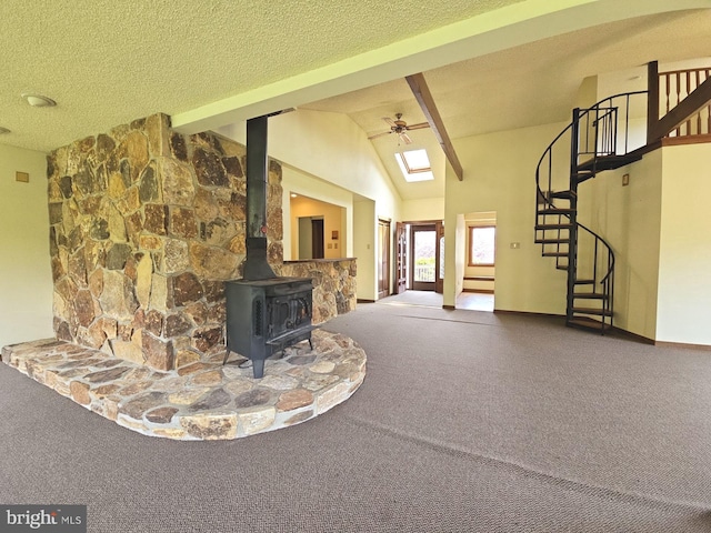 unfurnished living room with a wood stove, stairway, vaulted ceiling with beams, a ceiling fan, and carpet floors