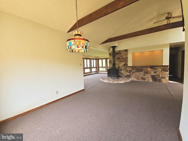 unfurnished living room with a wood stove, baseboards, carpet floors, a ceiling fan, and vaulted ceiling with beams