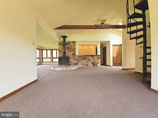 unfurnished living room with a ceiling fan, carpet flooring, a wood stove, and baseboards