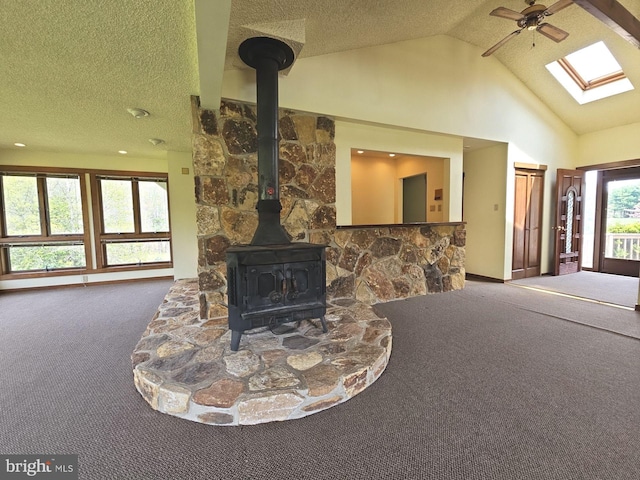 living room featuring a textured ceiling, a wood stove, ceiling fan, carpet floors, and high vaulted ceiling