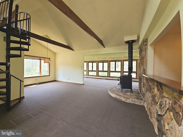 unfurnished living room with vaulted ceiling with beams, carpet, stairway, a wood stove, and a textured ceiling