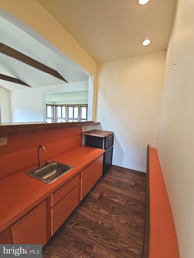 kitchen featuring recessed lighting, a sink, beam ceiling, dark wood-type flooring, and light countertops