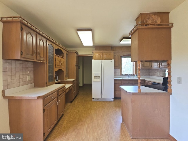 kitchen featuring tasteful backsplash, white refrigerator with ice dispenser, light countertops, a sink, and light wood-type flooring
