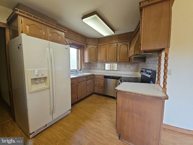 kitchen featuring stainless steel appliances, light countertops, light wood-style flooring, and backsplash