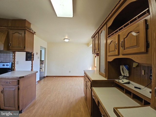kitchen with tasteful backsplash, light wood-type flooring, light countertops, and baseboards