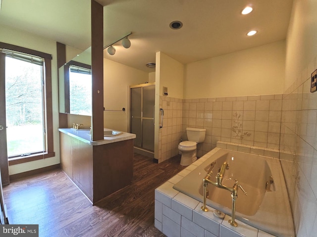 bathroom with a stall shower, toilet, a whirlpool tub, tile walls, and wood finished floors