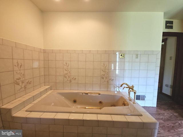 bathroom with a tub with jets and wood finished floors