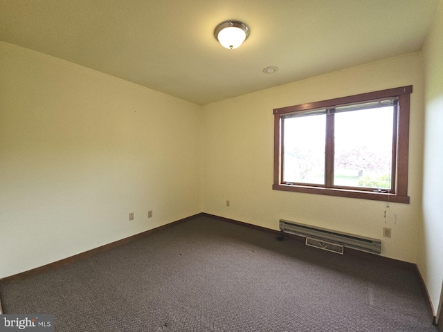 empty room with dark colored carpet, a baseboard radiator, and baseboards