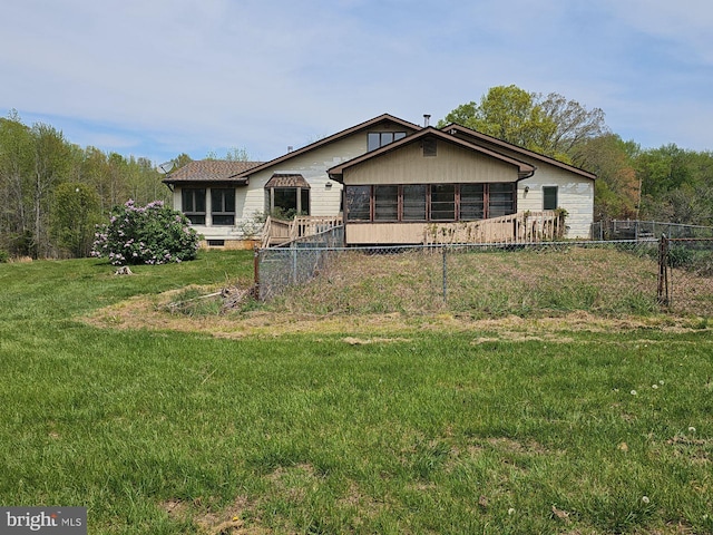 back of property featuring fence, a yard, and a sunroom