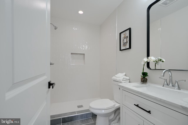bathroom with visible vents, vanity, tile patterned flooring, and tiled shower