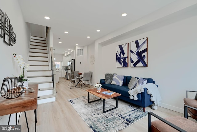 living area featuring visible vents, stairs, light wood finished floors, and recessed lighting