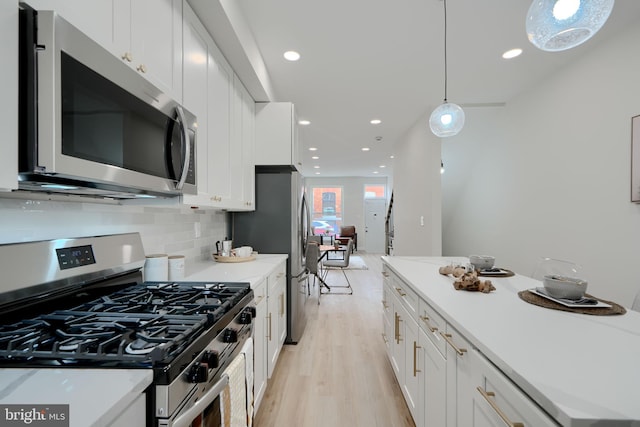 kitchen with white cabinetry, tasteful backsplash, stainless steel appliances, and light wood finished floors