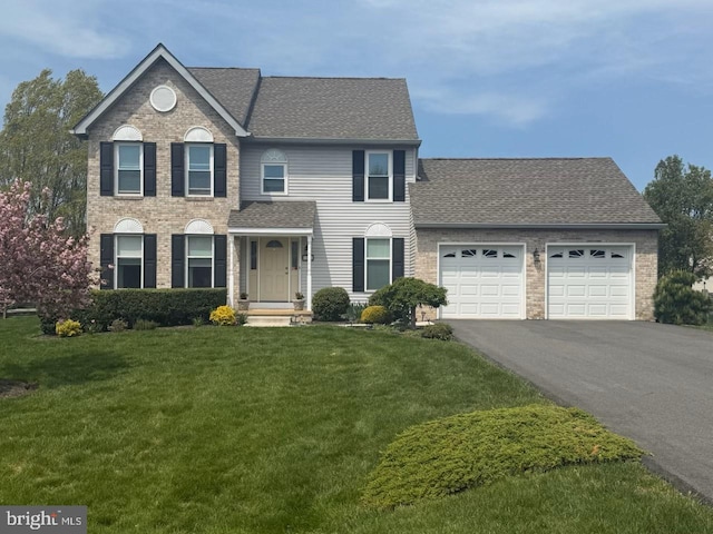 view of front facade with a garage, aphalt driveway, a front lawn, and roof with shingles
