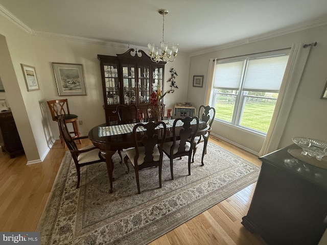 dining room featuring an inviting chandelier, wood finished floors, crown molding, and baseboards