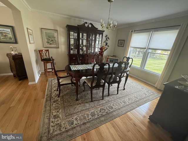 dining space with wood finished floors, a chandelier, crown molding, and baseboards
