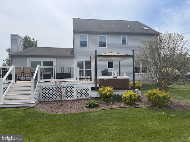 rear view of house with a wooden deck, a yard, a shingled roof, and a hot tub