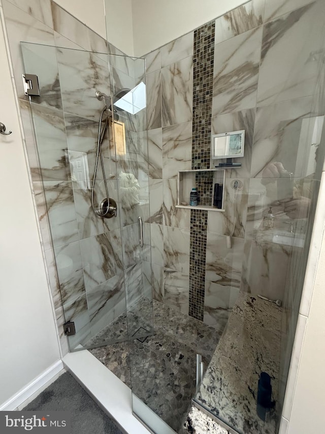 bathroom with a shower stall and baseboards