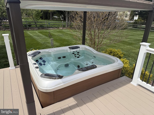 wooden deck featuring fence, a hot tub, and a lawn