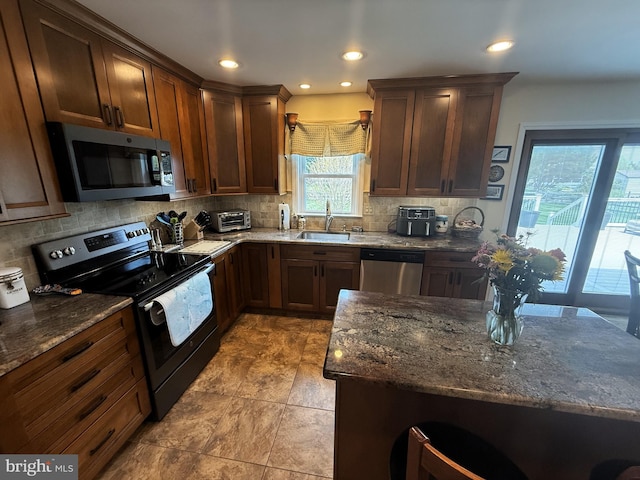 kitchen with tasteful backsplash, dark stone counters, a toaster, appliances with stainless steel finishes, and a sink