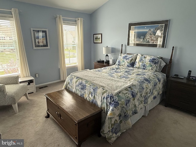 bedroom featuring lofted ceiling, visible vents, baseboards, and light carpet