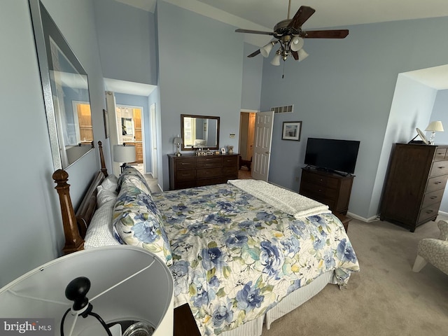 bedroom with a high ceiling, a ceiling fan, visible vents, baseboards, and light colored carpet