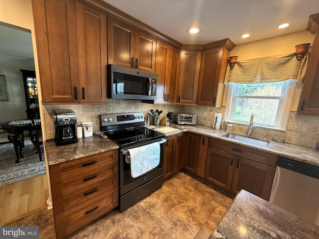 kitchen featuring decorative backsplash, a toaster, stainless steel appliances, stone counters, and a sink