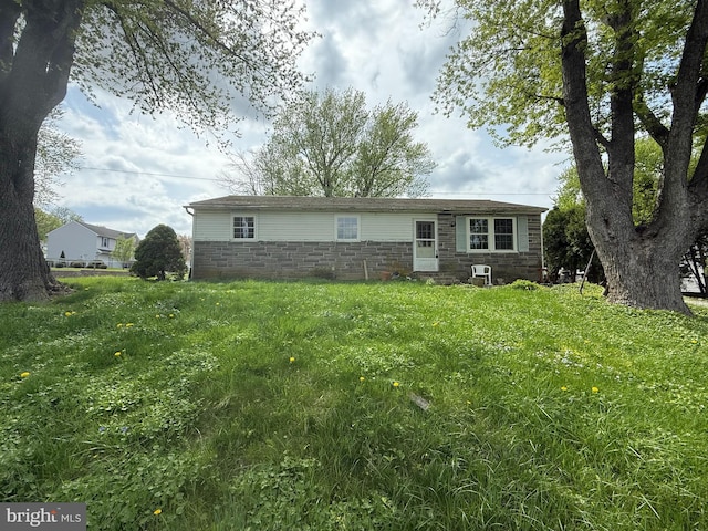 view of front facade featuring cooling unit, a front yard, and stone siding