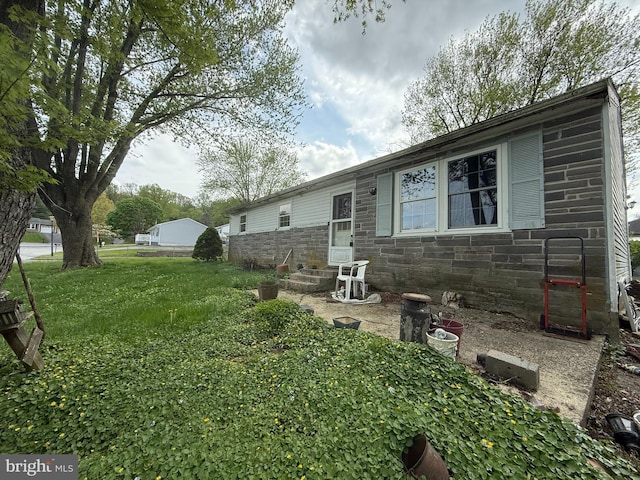 ranch-style home featuring a front lawn, stone siding, and entry steps