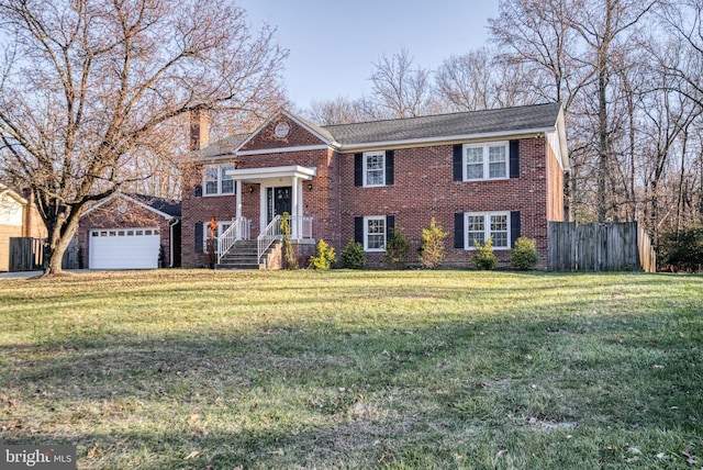 raised ranch featuring a front yard, a chimney, a garage, and brick siding