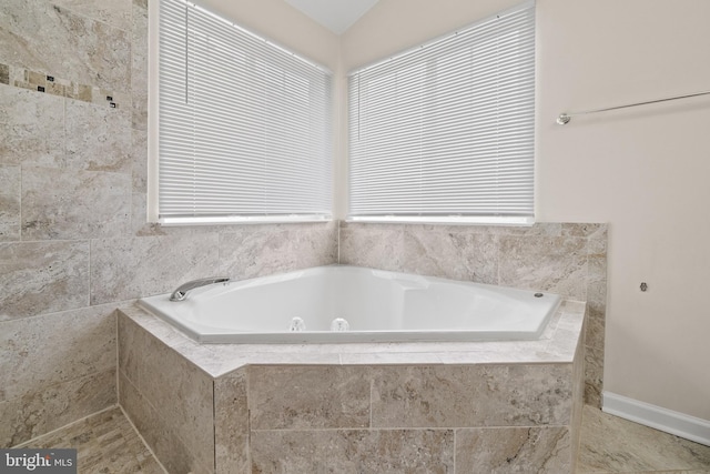 full bath featuring a garden tub and baseboards