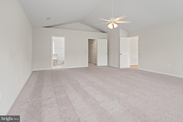 unfurnished bedroom featuring lofted ceiling, carpet, baseboards, and a walk in closet