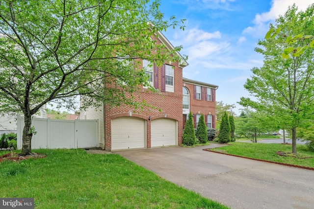 view of front facade with brick siding, fence, aphalt driveway, and a front yard