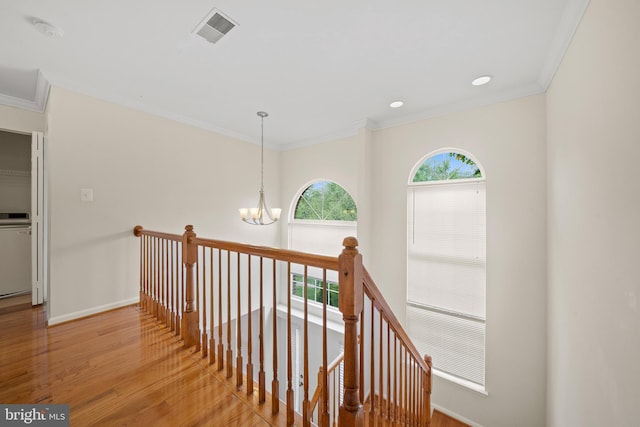 corridor featuring an upstairs landing, a notable chandelier, crown molding, visible vents, and wood finished floors