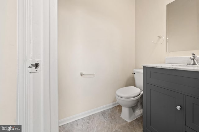 half bathroom featuring baseboards, toilet, and vanity