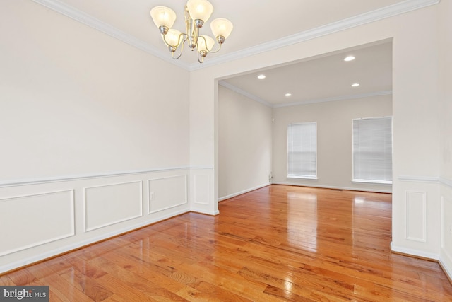 empty room with an inviting chandelier, a wainscoted wall, recessed lighting, and light wood finished floors