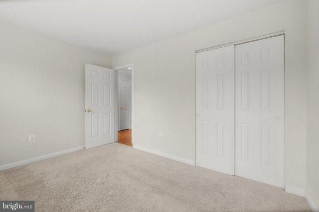 unfurnished bedroom featuring a closet, carpet flooring, and baseboards