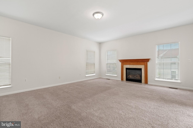 unfurnished living room featuring a tile fireplace, visible vents, carpet flooring, and baseboards