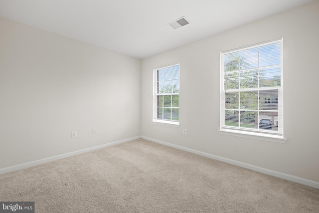 carpeted spare room with visible vents and baseboards