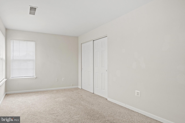 unfurnished bedroom featuring visible vents, a closet, carpet flooring, and baseboards