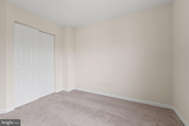 unfurnished bedroom featuring baseboards, a closet, and carpet