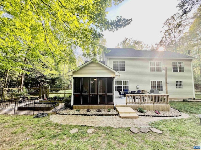 back of house featuring a sunroom, a deck, a lawn, and a chimney