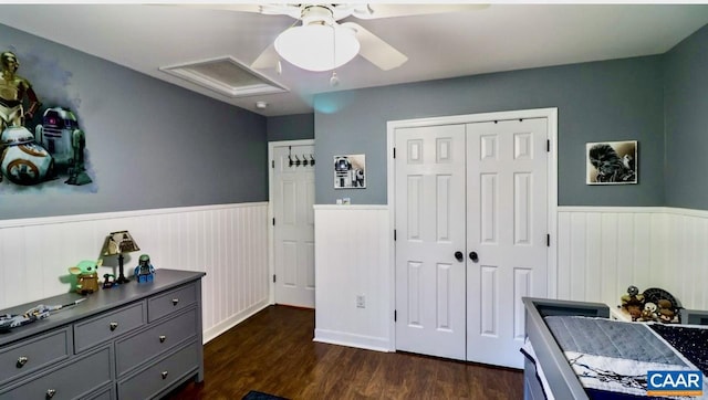bedroom featuring dark wood-style flooring, ceiling fan, a closet, and wainscoting