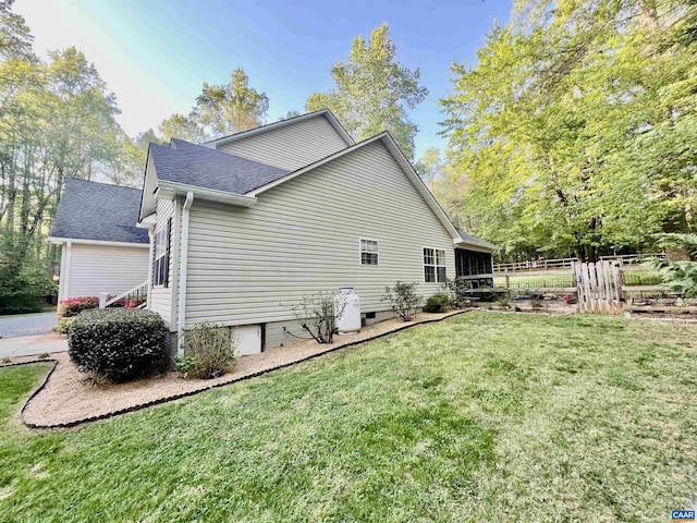 view of side of property with a lawn, fence, and a shingled roof